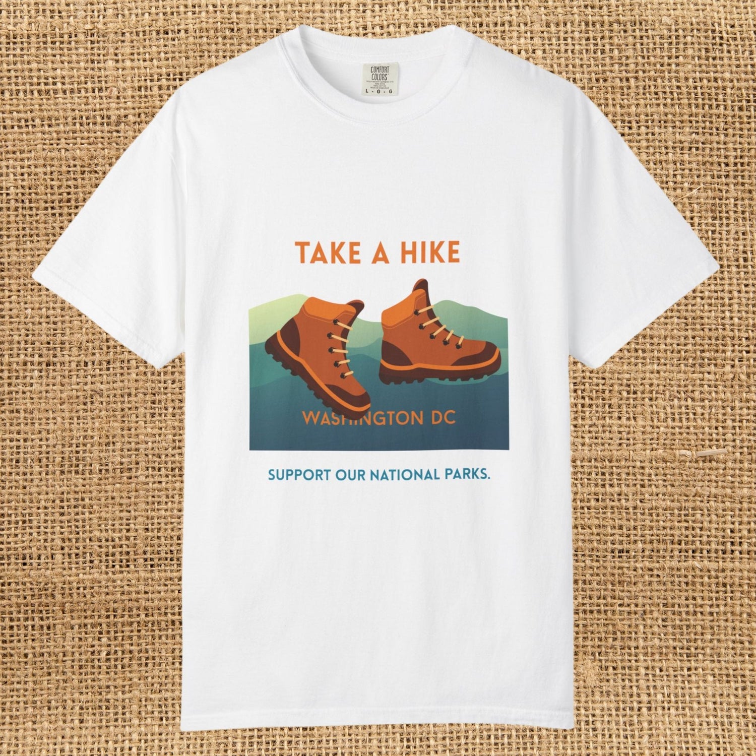 Graphic tee with cartoon-style hiking boots. Text says "Take a hike Washington DC.  Support our national parks."