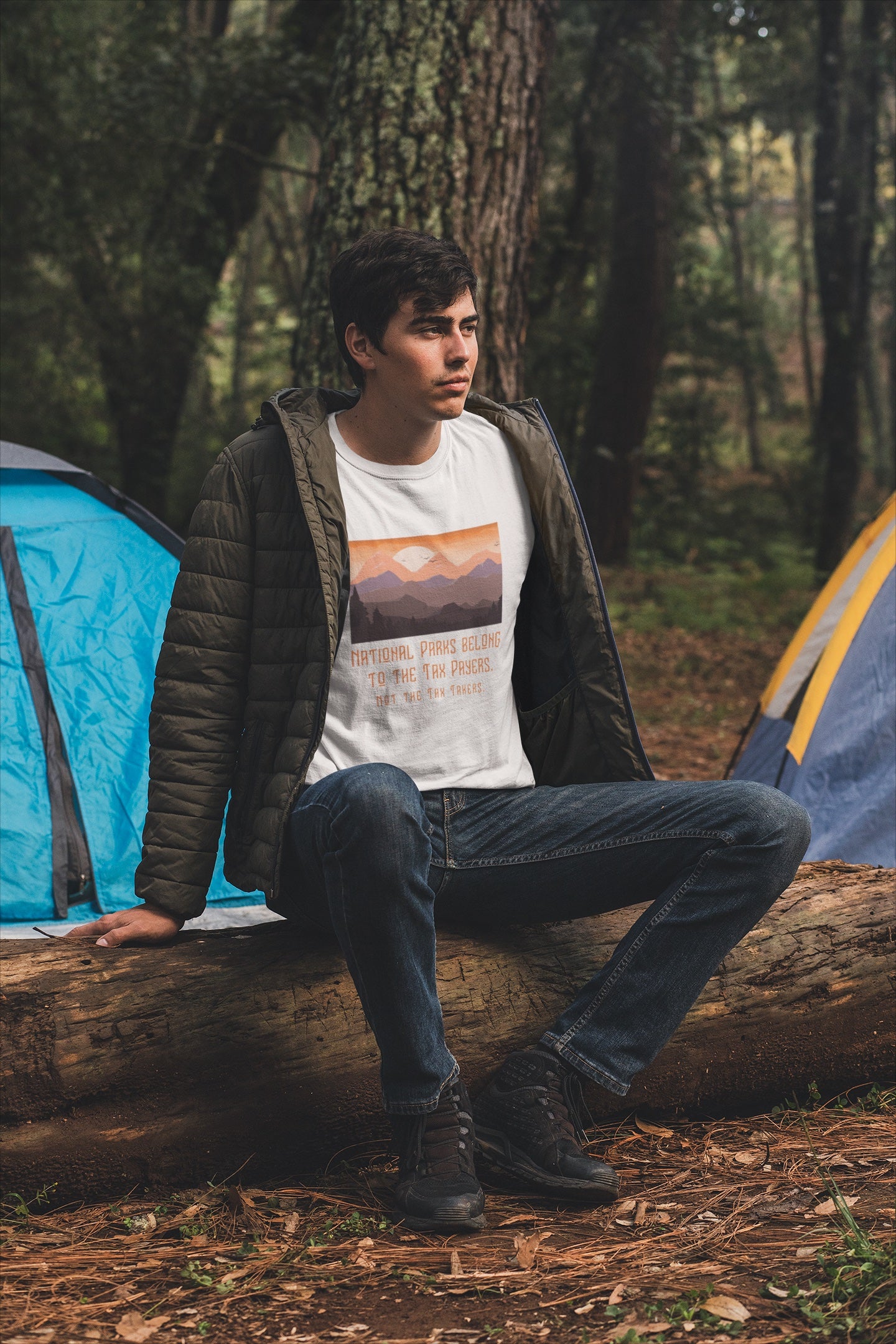 Person sitting on a log in a forest with camping tents in the background