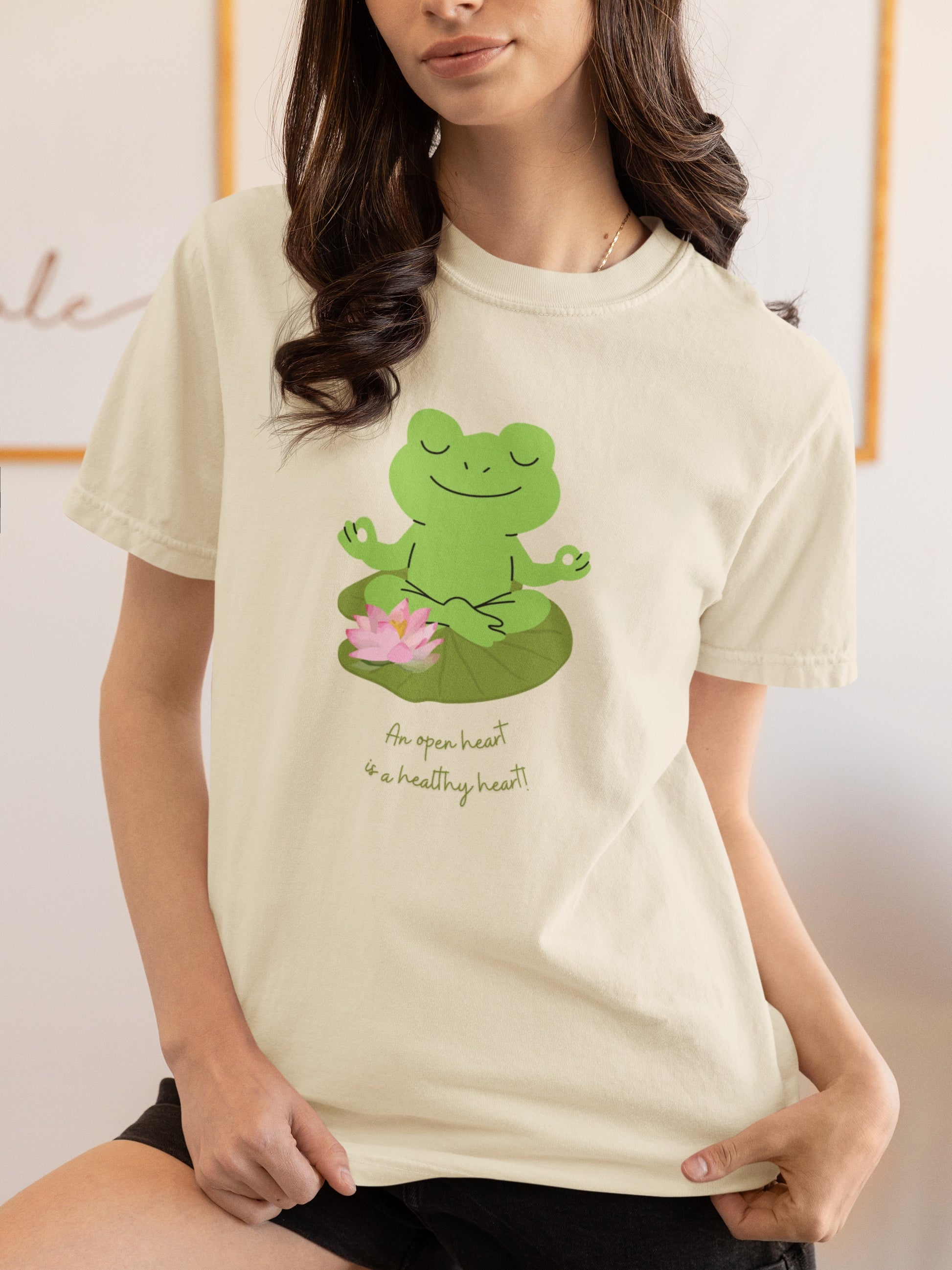 Person wearing a cream t-shirt with a green frog design and text.