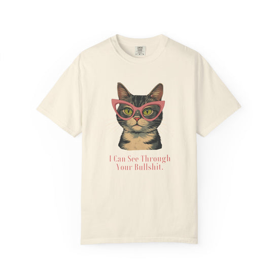 An off-white short-sleeve t-shirt with a graphic of a tabby cat wearing pink glasses and the text 'I Can See Through Your Bullshit.' printed below, displayed on a clean white background.