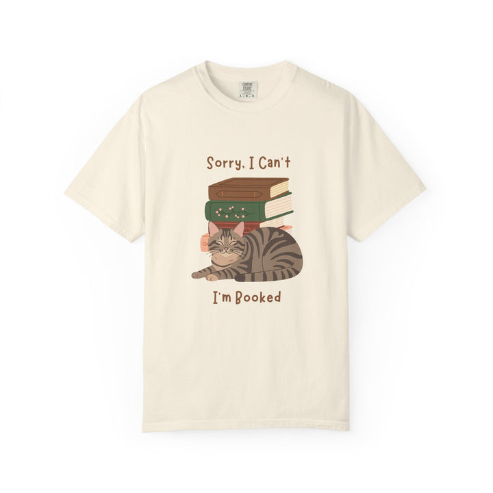 White cotton tshirt with graphic of a cat laying in front of stack of books.  Text says, Sorry, I can't.  I'm booked.
