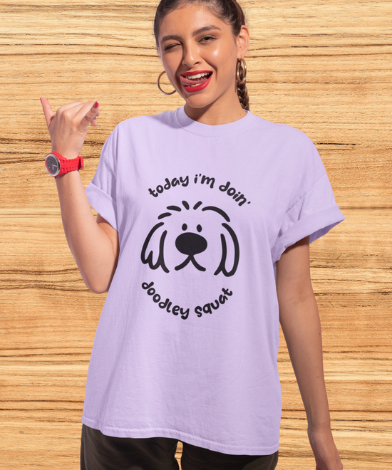 Purple short-sleeve crewneck t-shirt featuring a black graphic of a dog's face with the text 'Today i'm Doin' Doodley Squat" displayed on a clean white background.