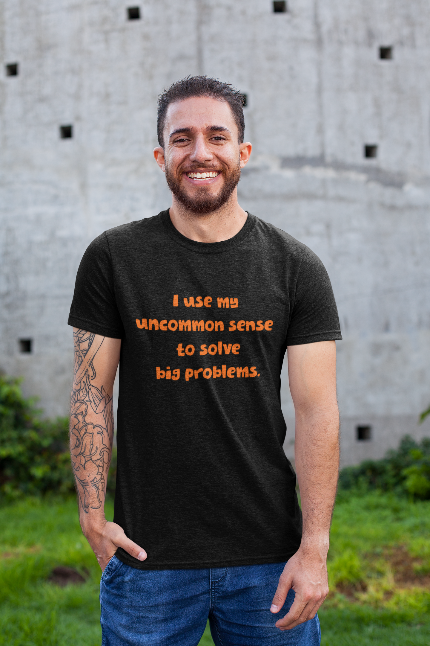 Black short sleeve, crew neck t-shirt has orange type that says "I use my uncommon sense to solve big problems."