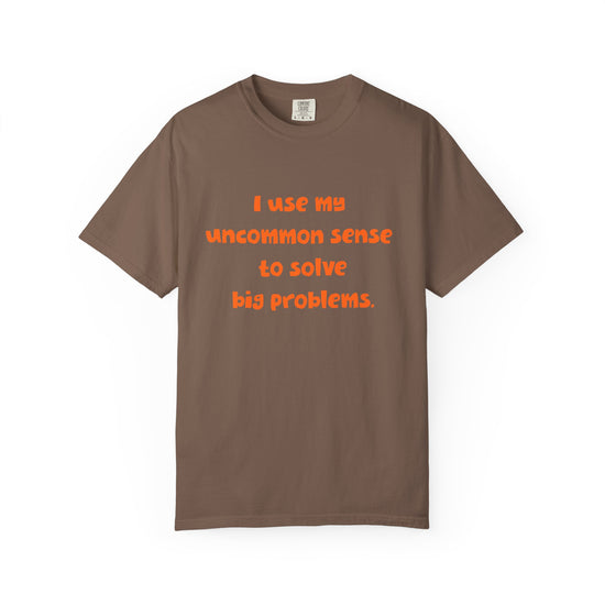 Brown short sleeve, crew neck t-shirt has orange type that says "I use my uncommon sense to solve big problems."