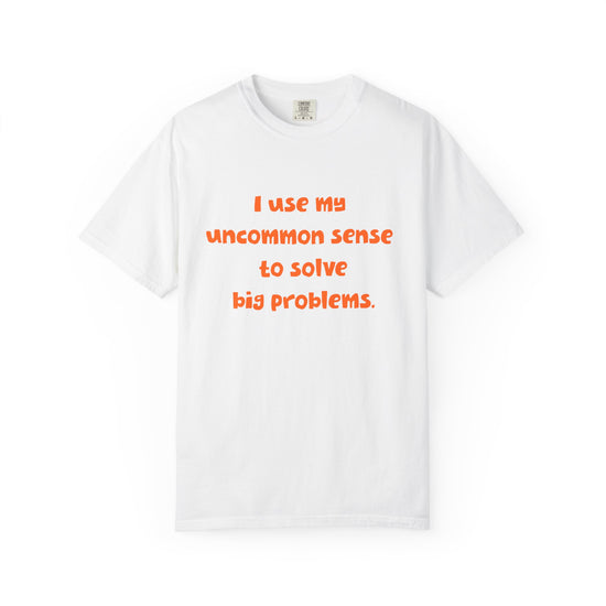 White short sleeve, crew neck t-shirt has orange type that says "I use my uncommon sense to solve big problems."