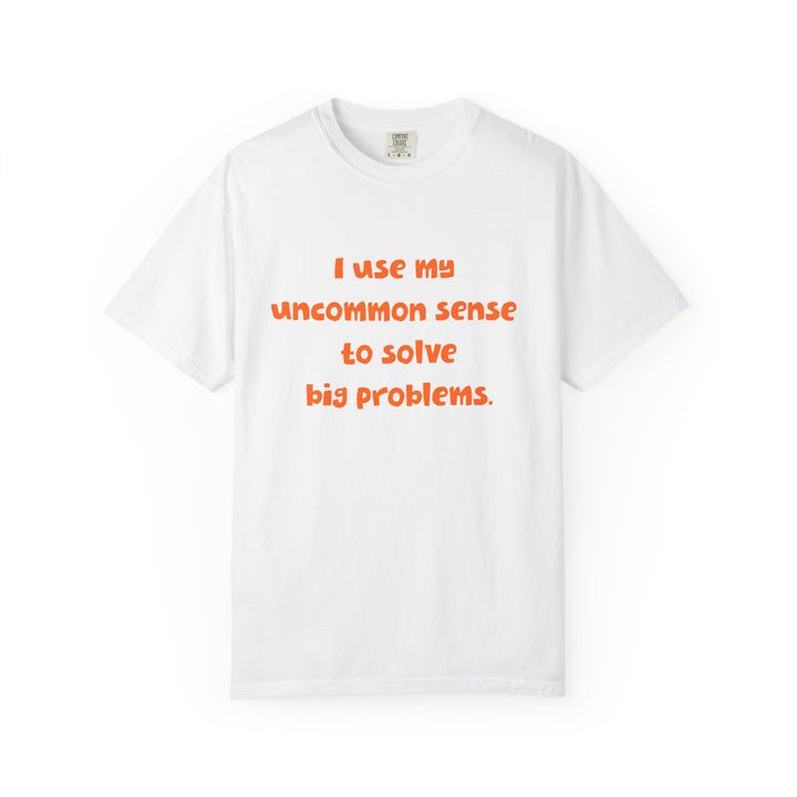 White short sleeve, crew neck t-shirt has orange type that says "I use my uncommon sense to solve big problems."