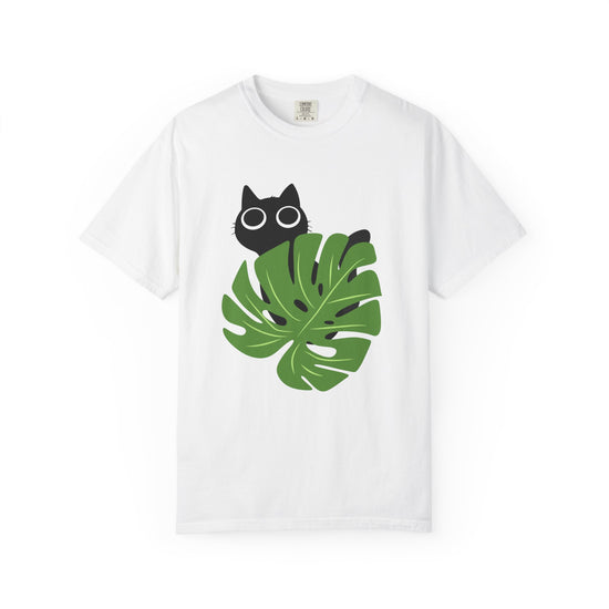 A white short-sleeve crewneck t-shirt featuring a graphic print of a black cat peeking from behind a large green monstera leaf on the front.