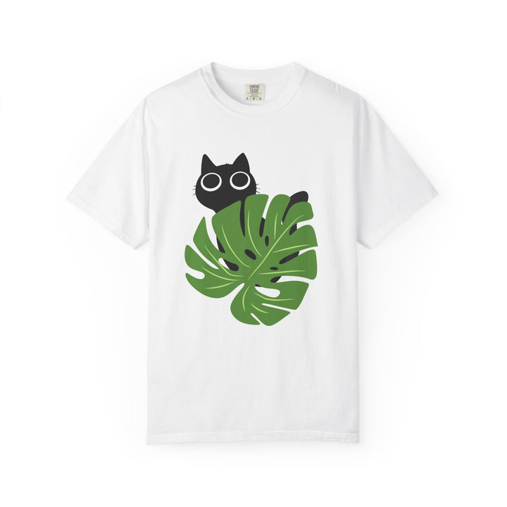 A white short-sleeve crewneck t-shirt featuring a graphic print of a black cat peeking from behind a large green monstera leaf on the front.