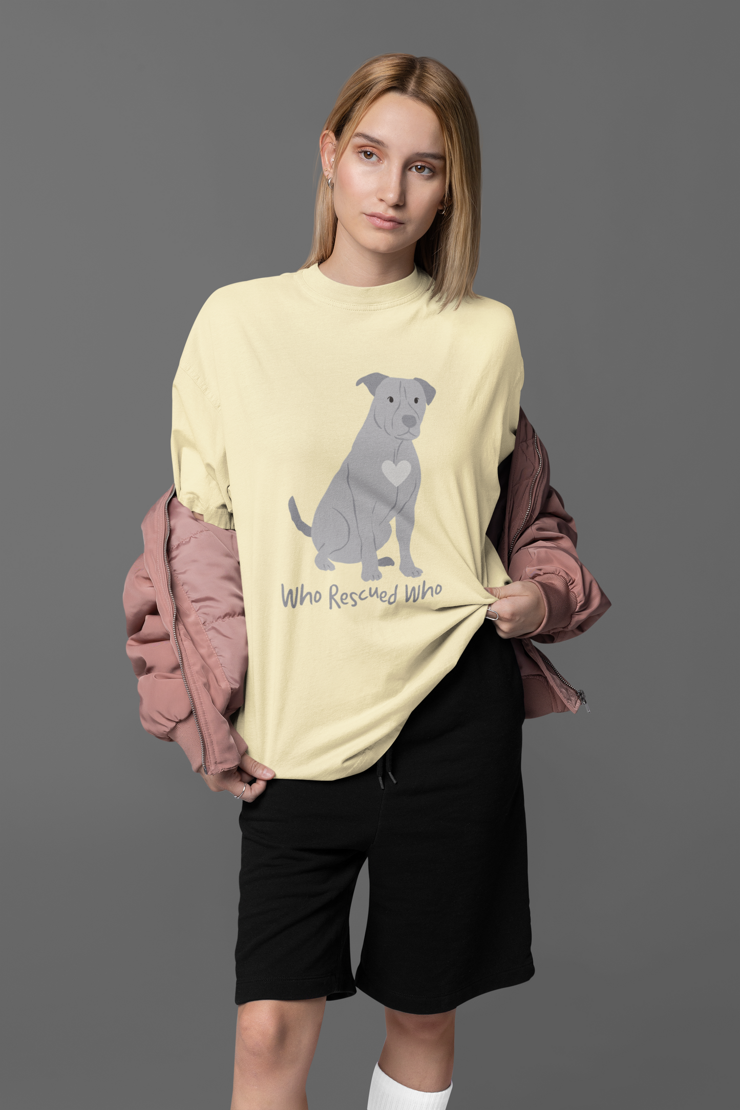Yellow short-sleeve crewneck t-shirt featuring a graphic of a pit bull dog with a white heart on its chest sitting and the text 'Who Rescued Who' printed below it.