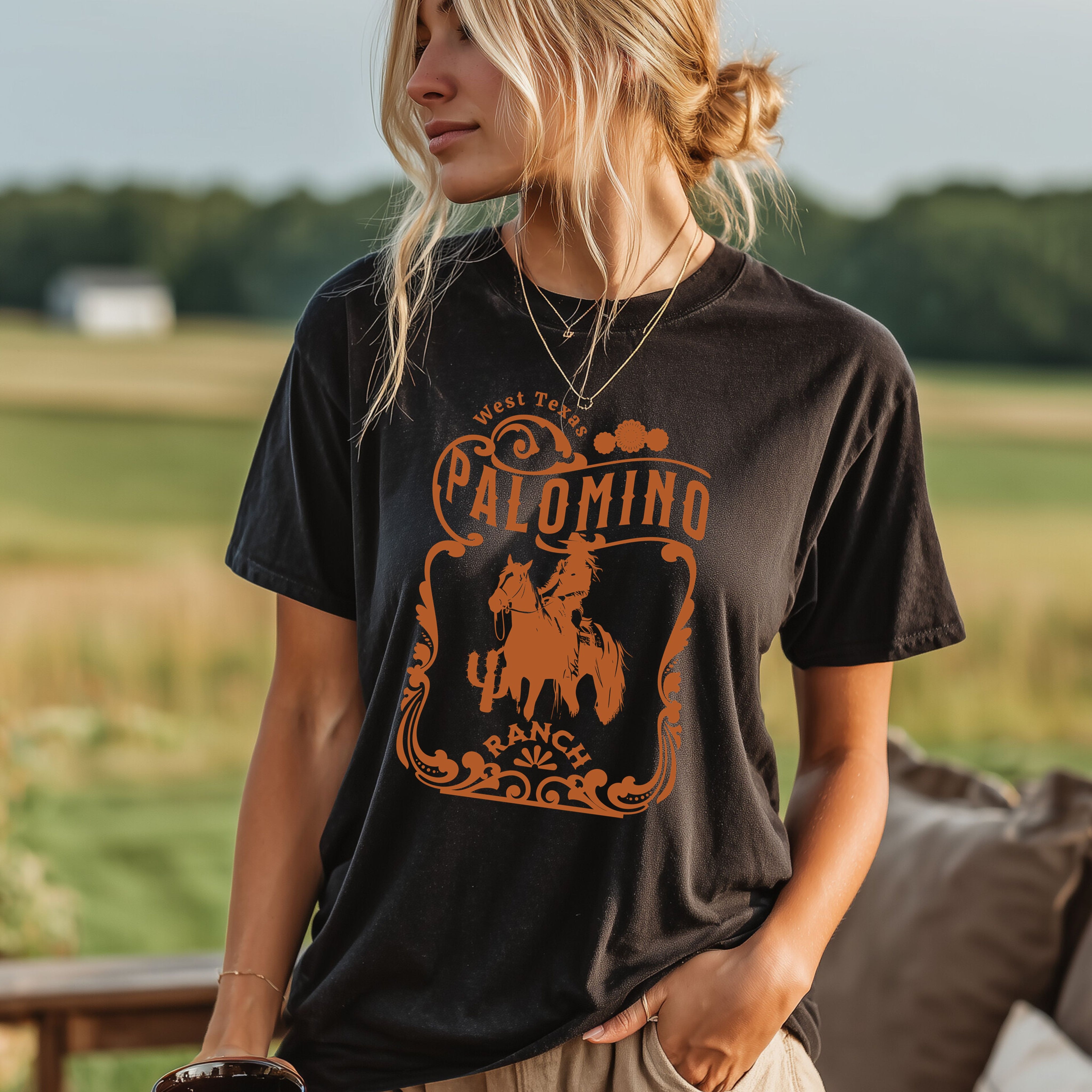 Black t-shirt with a graphic design of a horse and rider, and 'Palomino Ranch' text .Worn by woman